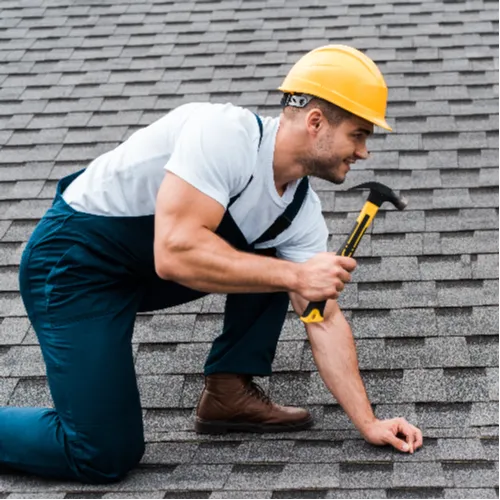 A roofing technician applying sealant around a cracked tile and flashing to complete an emergency roof leak repair on a residential home.