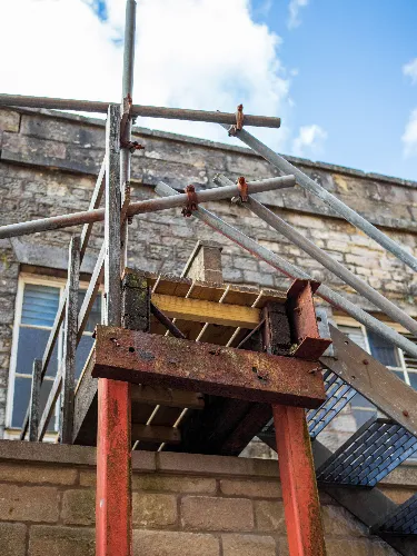 Two roofers working on a metal commercial roof to carry out urgent emergency roof repairs after severe storm damage.