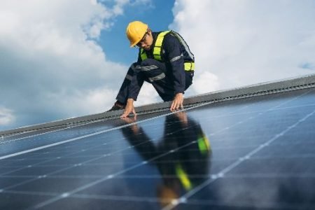 Technician inspecting solar panels on roof
